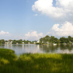 Landscape image looking from one shore to another tree lined shoreline on a sunny day.