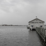 Landscape photo of a boat house at the end of a dock on an overcast day.