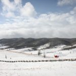 Landscape of idyllic snow covered rolling hills stretched to mountains beyond on a sunny day.